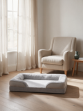 The Ridge orthopedic sofa dog bed in light grey on pale oak floorboards beside a linen armchair, Australian living room